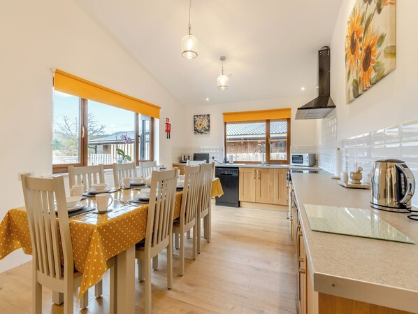 Un comedor con una mesa dispuesta para cuatro personas, una cocina equipada con electrodomésticos modernos y un amplio ventanal con vistas al exterior.