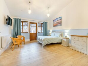 A bedroom with a bed, a dresser, a chair, a TV, and a door leading to an outdoor area. - Lime Lodge - UK42547 (Llandrindod Wells)