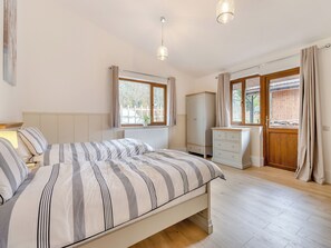 Un dormitorio con cama, cómoda, radiador y ventana con cortinas.