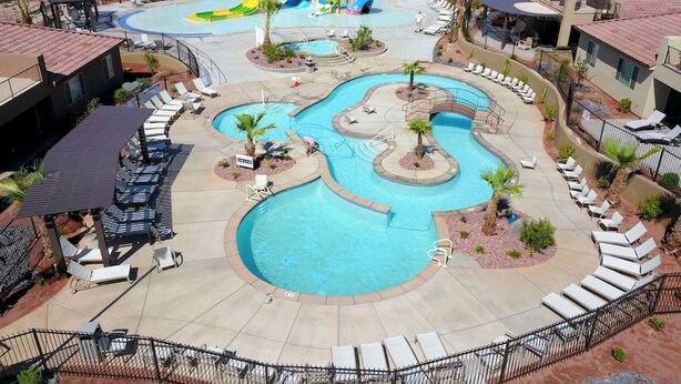 Un resort con un amplio área de piscina, numerosas tumbonas y un parque acuático.