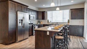 Una cocina moderna con armarios de madera oscura, electrodomésticos de acero inoxidable y una isla central con taburetes de bar.