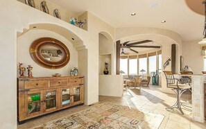 Un vaste espace de vie agrémenté d’un grand meuble en bois, d’un miroir rond et d’un tapis à motifs.