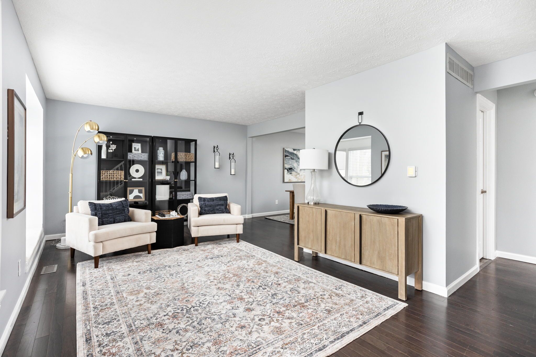 A living room with a sofa set, a coffee table, a rug, a cabinet, and a mirror.