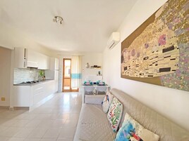Una cucina moderna con mobili bianchi, un fornello e un'area pranzo con tavolo e sedie.