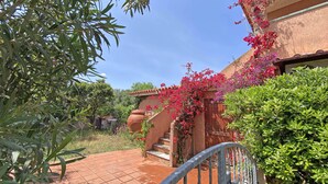 A courtyard with a tiled floor, a metal gate, and a building with a stucco exterior. - Sunset House PuntoCasaBudoni (San Teodoro)