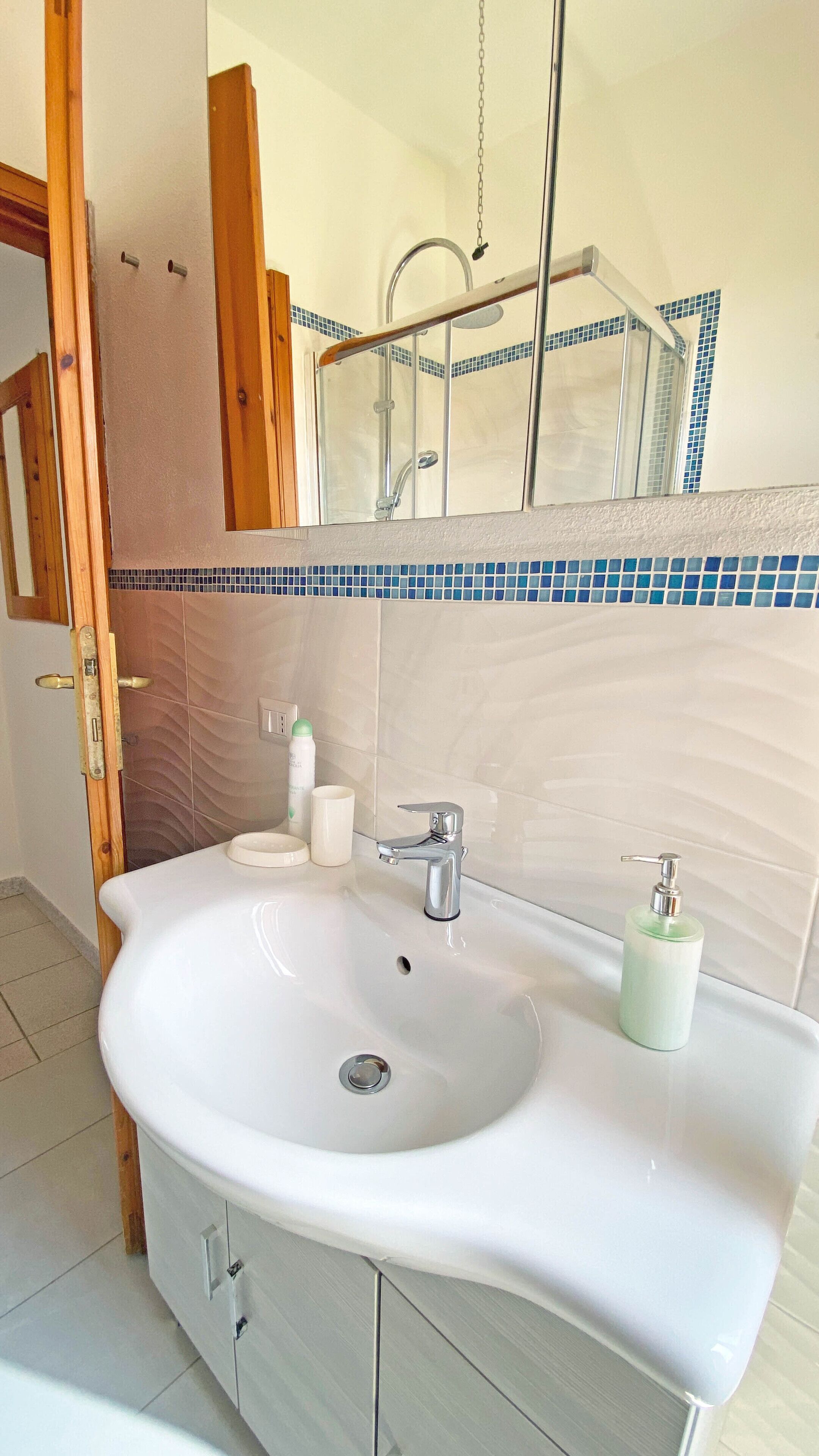 Une salle de bain avec un lavabo blanc, un miroir et un espace douche.