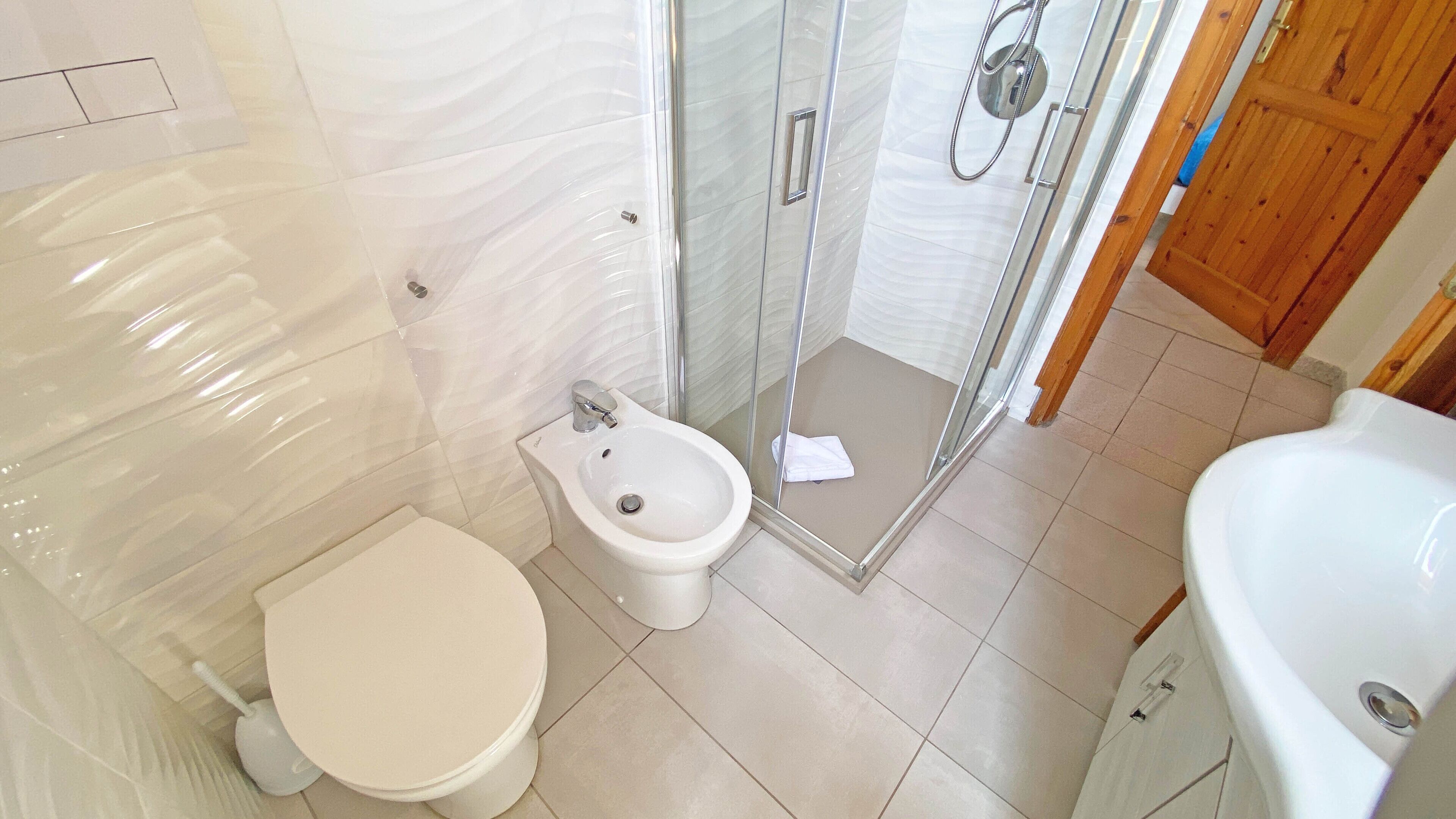 A bathroom with a toilet, bidet, glass shower enclosure, and a bathtub.