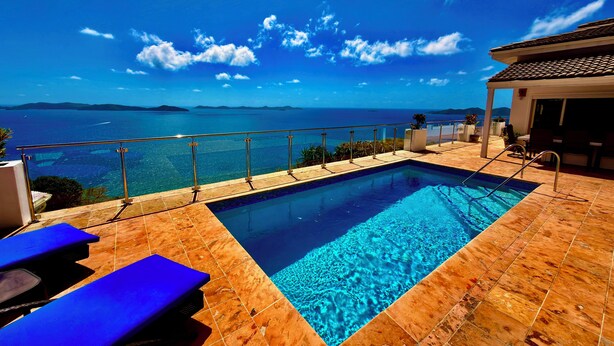 Une piscine à l’eau d’un bleu cristallin, une terrasse carrelée et une vue sur la mer.