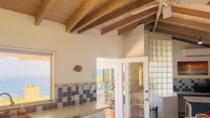 Une cuisine avec vue sur la mer, un ventilateur de plafond et un pare-feu en carreaux.