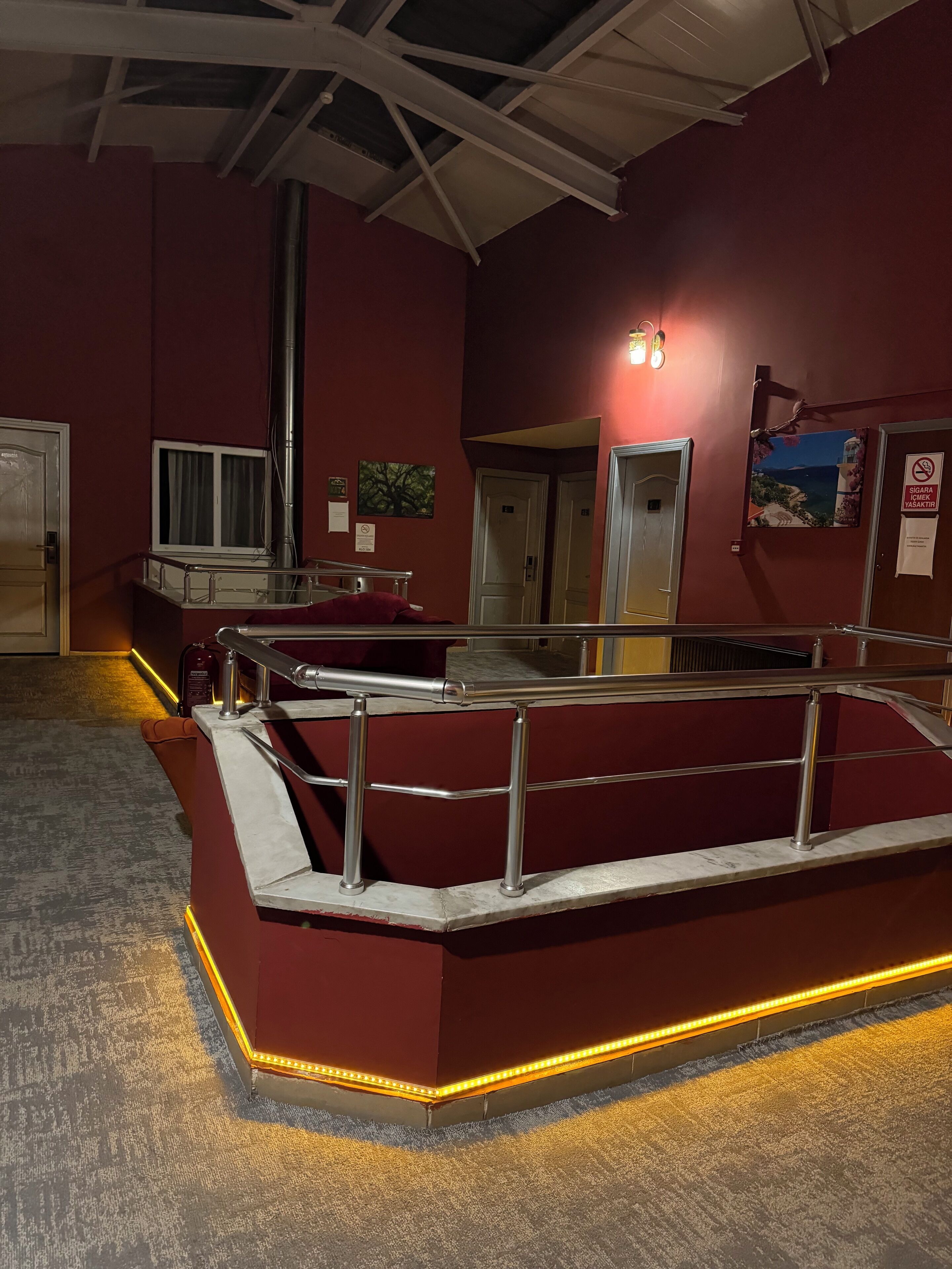 A hotel lobby with a red seating area, a staircase, and a view of the sea.