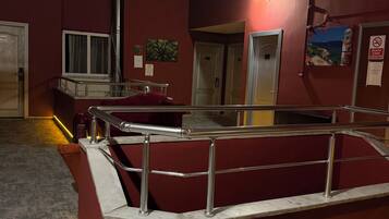 A hotel lobby with a red seating area, a staircase, and a view of the sea.