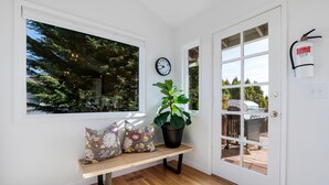 A room with a bench, a potted plant, a clock, and a door leading to an outdoor deck. - Alder House: A Single Level Home in Dundee Hills (Dundee)