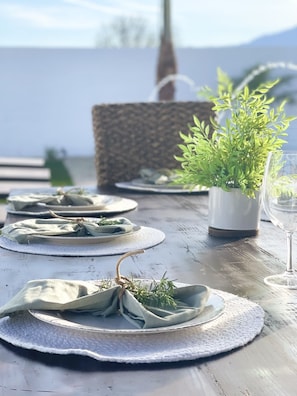 A wooden table set with plates, cloth napkins, a potted plant, and a glass of water.