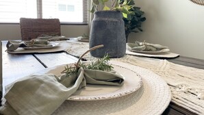 Une table à manger dressée avec des assiettes, des serviettes en tissu et une plante en pot.