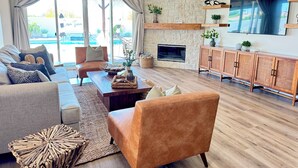 Un salon spacieux avec un mur en pierre, une cheminée, un téléviseur et une vue sur une piscine.