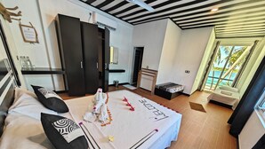 A spacious bedroom with a large bed, a wardrobe, and a view of the ocean.