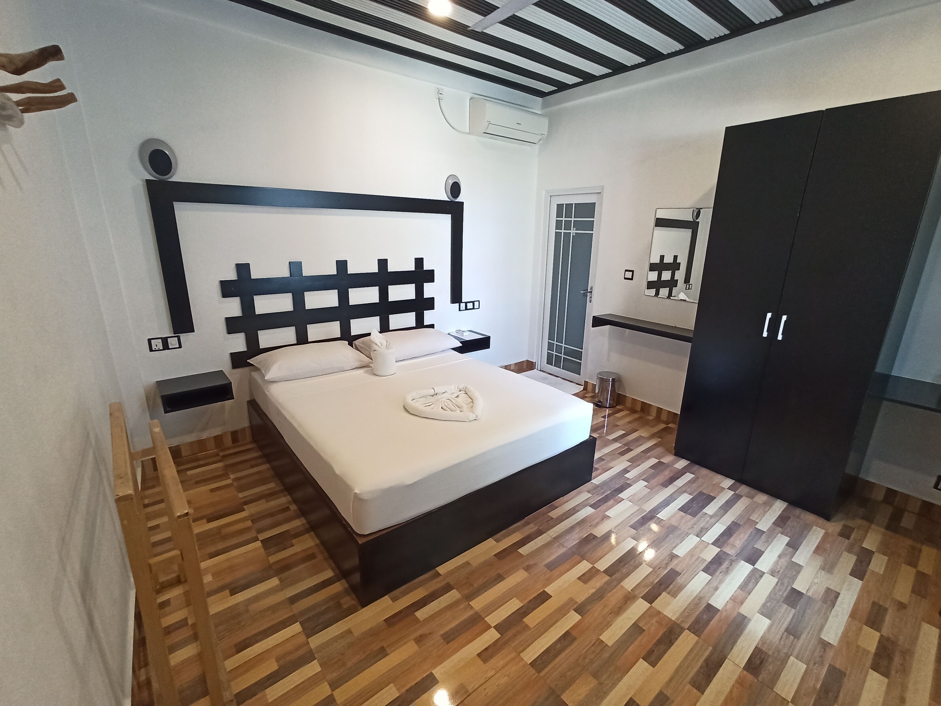 Ein Schlafzimmer mit Bett, Nachttischen, einem Kleiderschrank und einem Fenster.