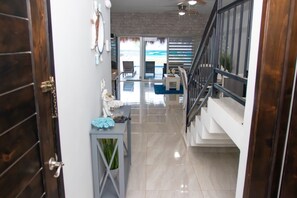 Un intérieur moderne avec un escalier, un couloir menant à une vue sur la plage et un coin repas.