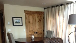 Una sala de estar con un sofá de cuero marrón, una mesa de comedor con sillas, un tapete mullido y un mueble de madera.