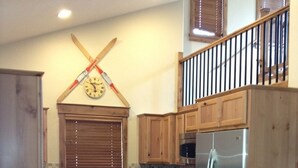Una cocina con armarios de madera, un refrigerador de acero inoxidable, un microondas, una estufa y un reloj en la pared.