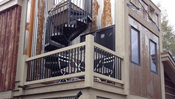Un edificio de varios pisos con una escalera espiral central, ventanas grandes y barandilla de metal.