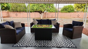 An outdoor patio area with wicker furniture, a central table, and a patterned rug.