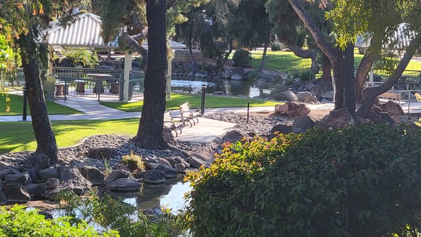 A landscaped garden with a pond, benches, and a gazebo.