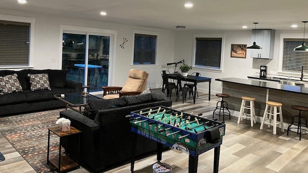 Een moderne woonkamer met een tafelvoetbalspel, een eethoek en een keuken.