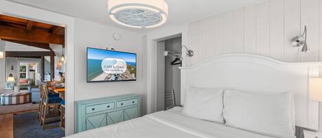 Una habitación de hotel con una cama, un televisor que muestra una vista panorámica, una lámpara de techo y una lámpara de pared.