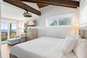Ein Schlafzimmer mit einem großen Bett, einem Deckenventilator, Blick auf den Ozean und einem Fenster mit Jalousien.