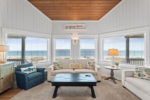 Ein geräumiges Wohnzimmer mit Blick auf den Ozean, einer Holzbalkendecke und einem Schild mit der Aufschrift 'St. George Island'.
