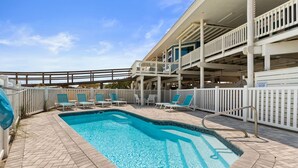 A swimming pool with lounge chairs and a covered area with railings.