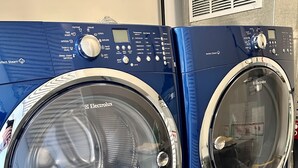 Two Electrolux front-loading washing machines in a laundry room.