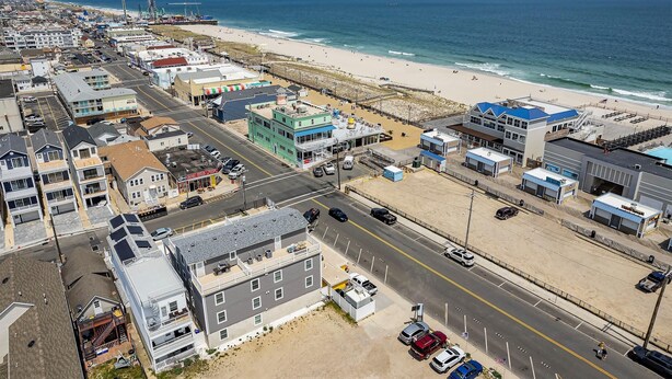 An aerial view of a coastal town with a beach, buildings, and a road.