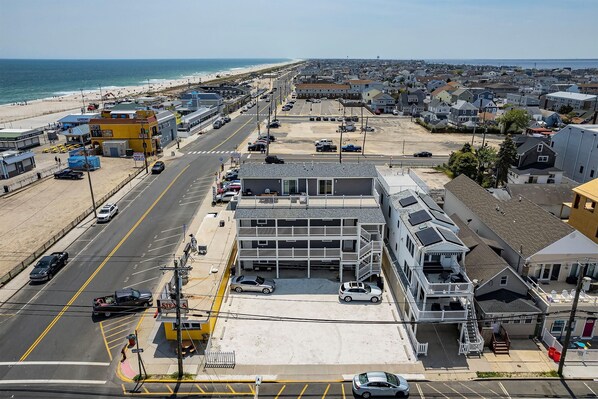 A coastal town with a beach, a parking lot, and a multi-story building with balconies.