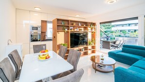 A modern living room with a dining area, a kitchen, and a balcony with outdoor furniture.