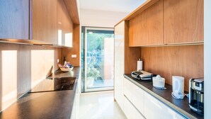 A modern kitchen with wooden cabinets, a black countertop, and a coffee machine.
