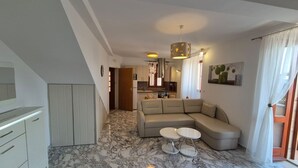 A modern living room with a marble floor, a beige sectional sofa, and a dining area with a small table and chairs. - Villa Ana Apartments - One Bedroom Apartment with Terrace and Sea View (Mlini)