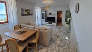 A modern living room with a dining area, a TV, and a view of the sea. - Villa Ana Apartments - One Bedroom Apartment with Terrace and Sea View (Mlini)