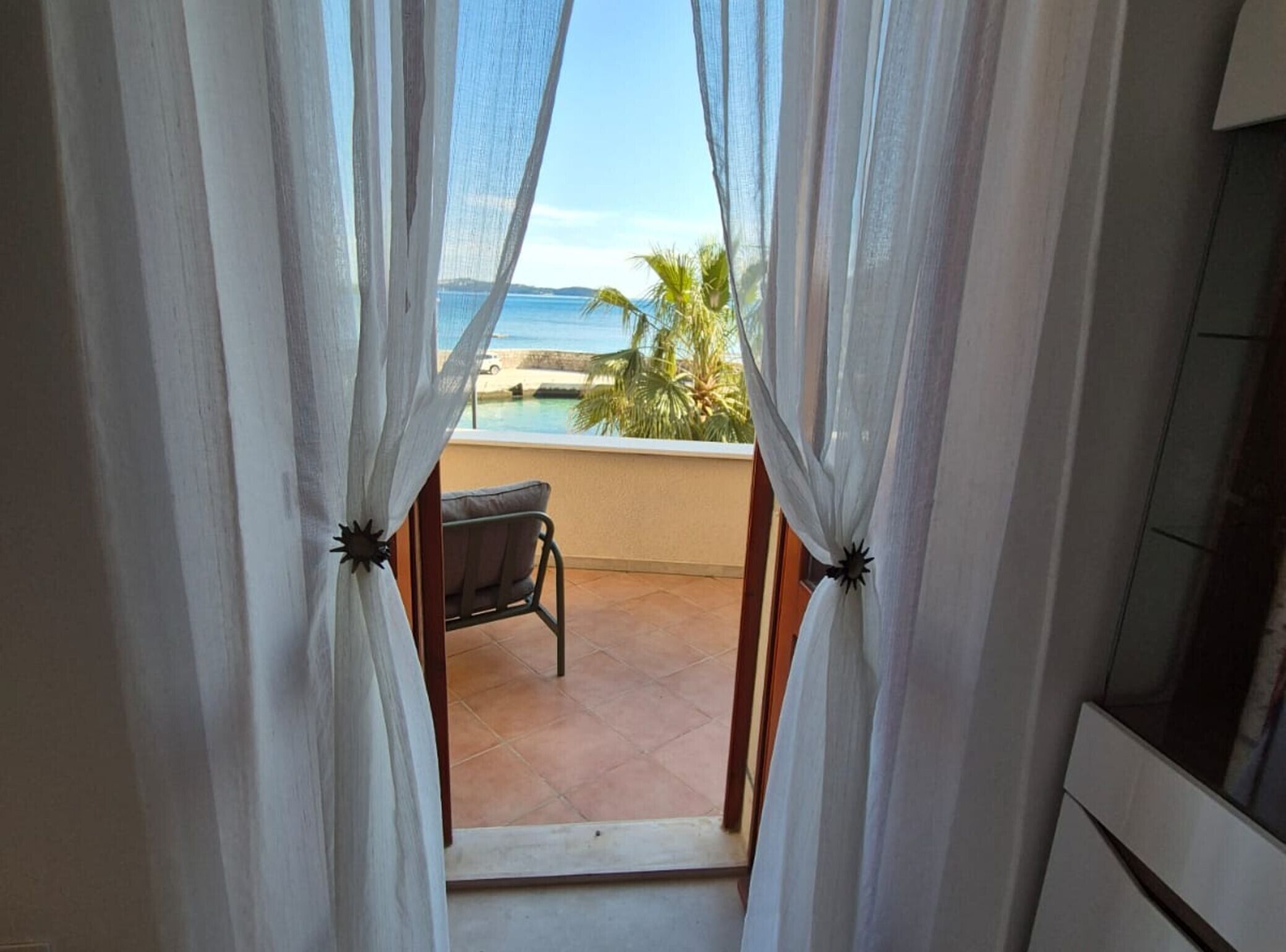 Un balcón con vista al mar, una silla y un televisor.