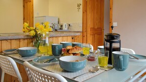 En matplats med ett bord dukat för frukost, inklusive croissanter, kaffe och en vas med blommor.