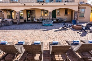 Une terrasse extérieure avec des fauteuils de jardin en osier, un barbecue et un espace salon abrité.