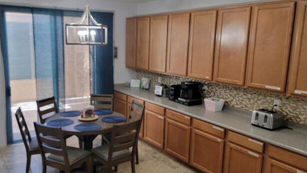 A kitchen with wooden cabinets, a dining table with blue placemats, and a chandelier. - 6BR 5BA, Heated Pool/Spa, indoor & outdoor games, pickleball, MUCH MORE! (Glendale)