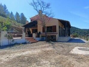Uma casa de dois andares com varanda coberta e escadaria de pedra até a entrada.