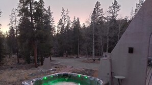 Un bain à remous sur une terrasse en bois, avec vue sur une zone boisée.