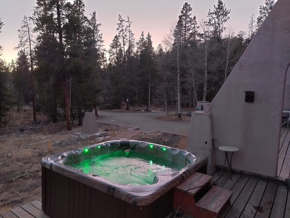 Un jacuzzi en una terraza de madera con vista a un área boscosa.