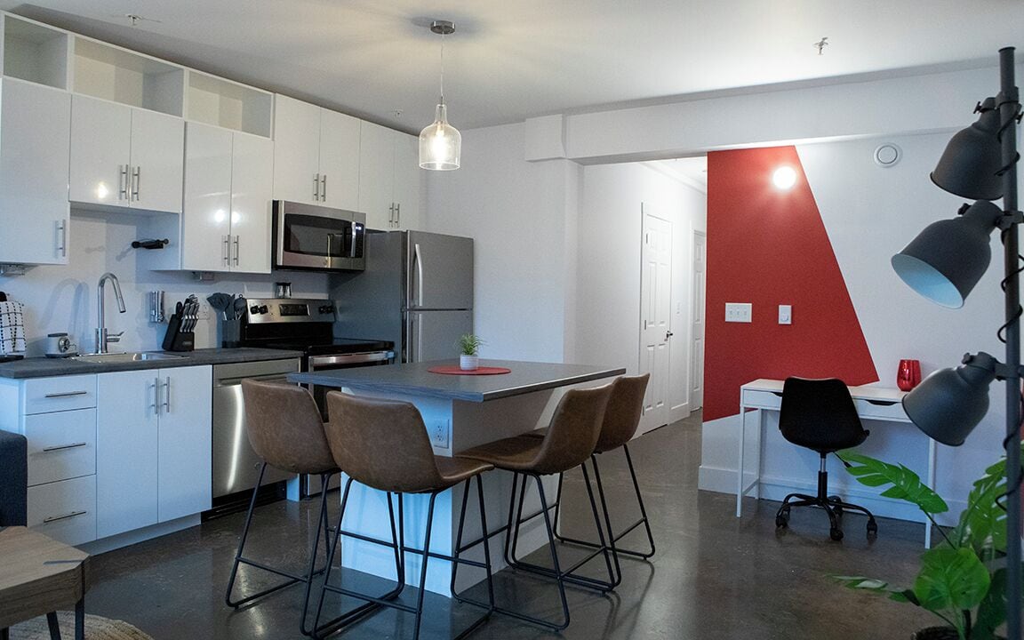 A modern kitchen with white cabinets, stainless steel appliances, and a central island with bar stools.