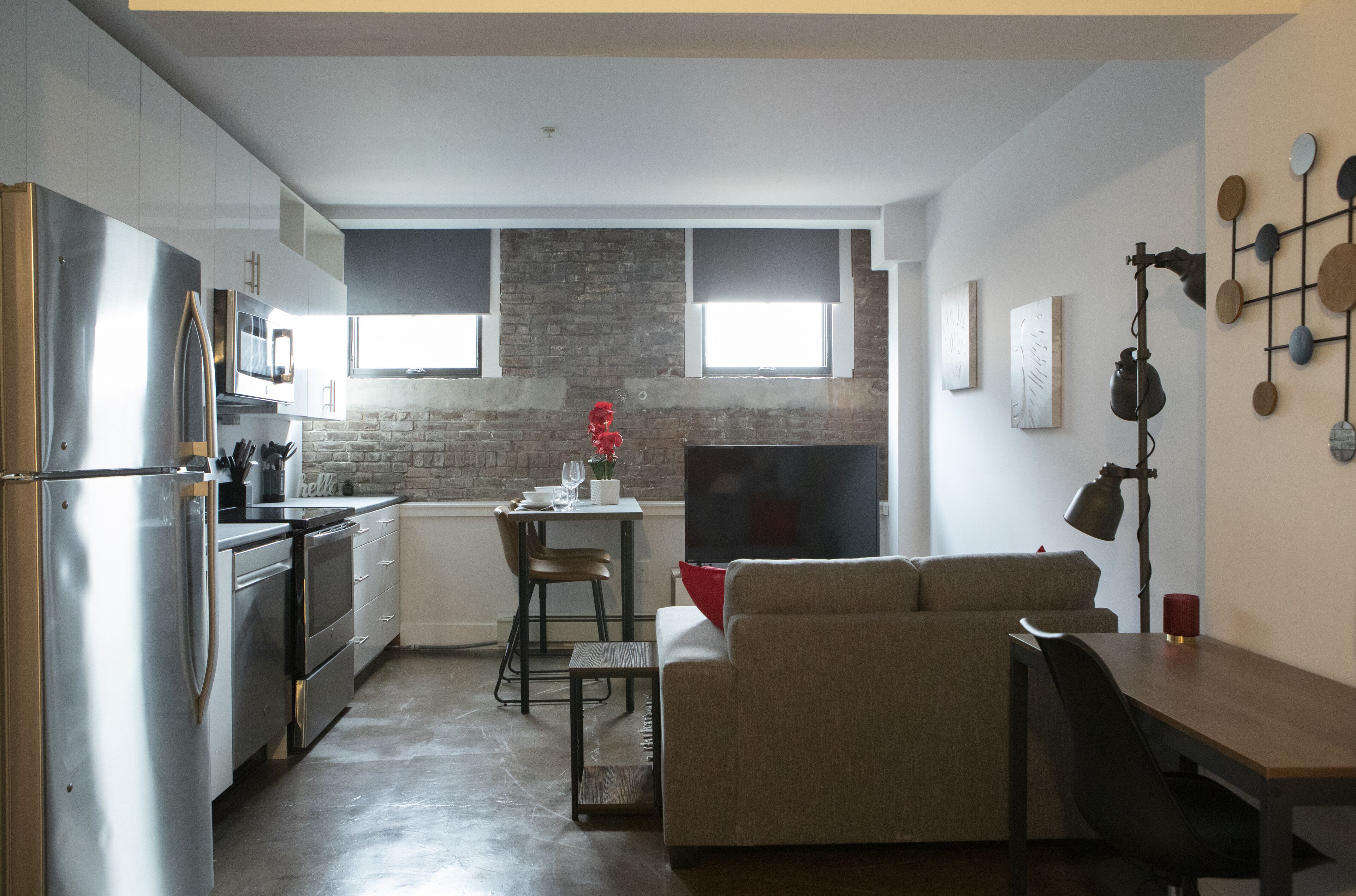 Un espace de vie compact comprenant un coin cuisine, un coin repas et un espace détente avec un canapé et une table basse.
