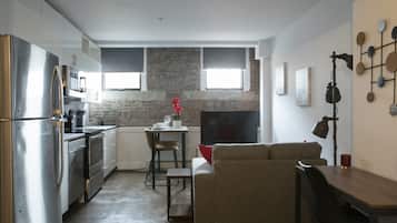 Un espace de vie compact comprenant un coin cuisine, un coin repas et un espace détente avec un canapé et une table basse.