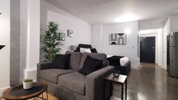 Un salon moderne avec un canapé gris, une petite table ronde en bois et une plante en pot.